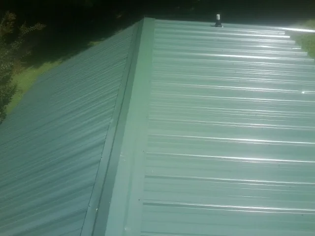 New green metal panels meeting at the ridge of a roof — Flat Roof Repair work by our crew in Hanover Park