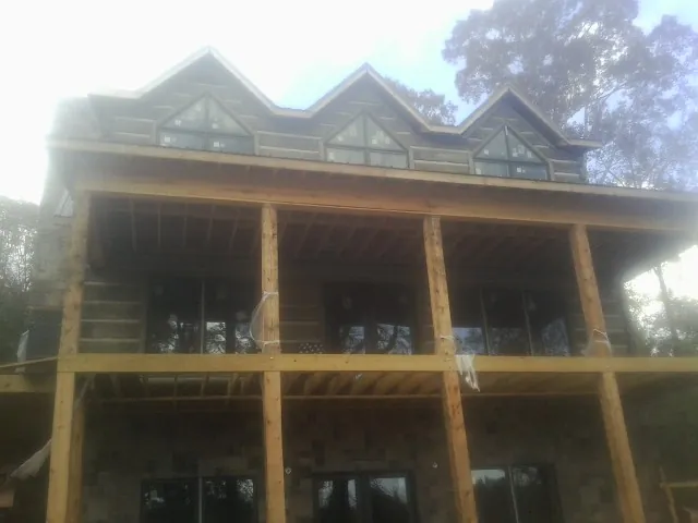 Dormers and porch framing on a large log home under construction — Roof Coating work by our crew in Hanover Park