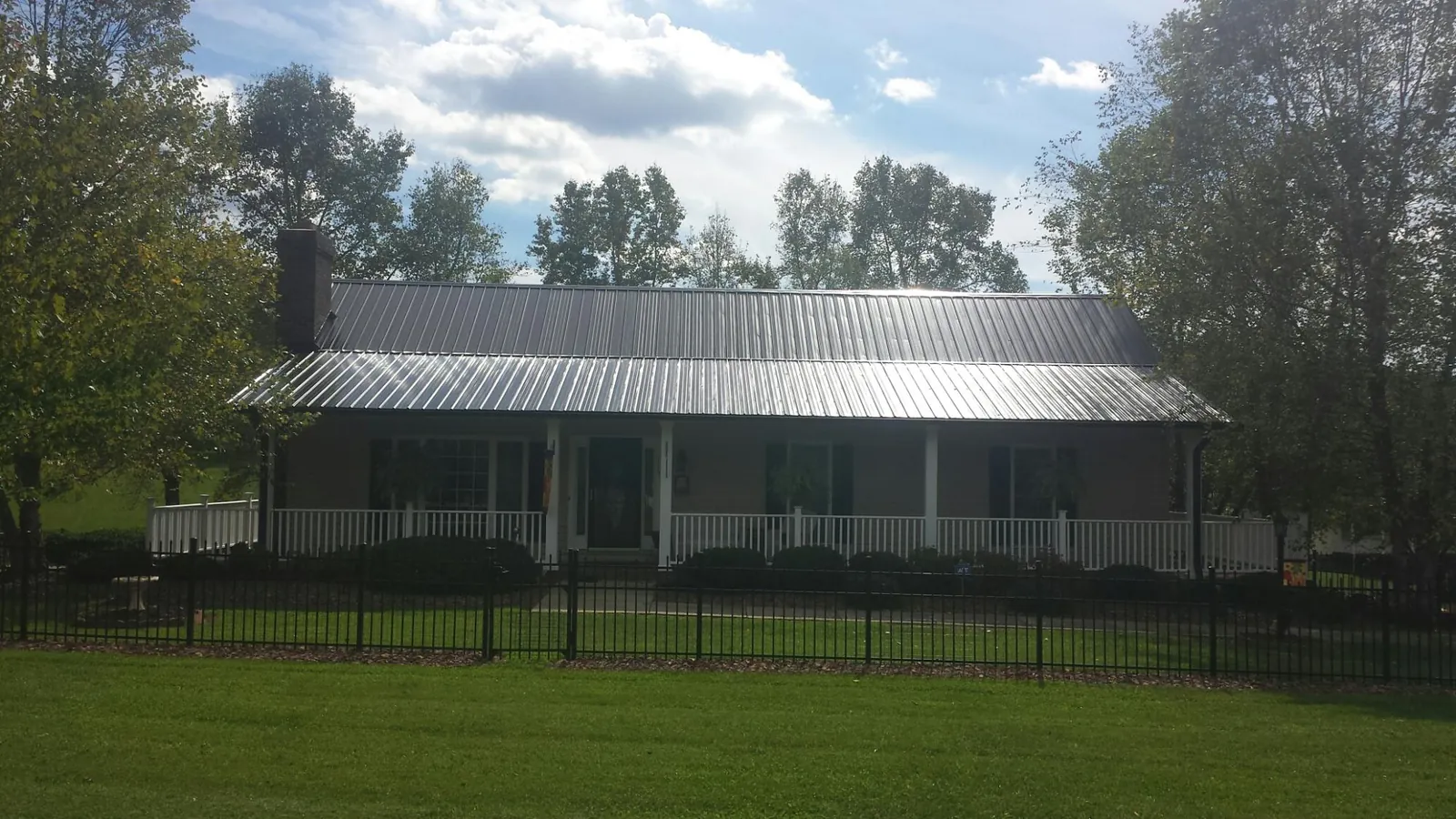 Gray metal roof on a brick ranch with a full width front porch — Gutter Guard Installation work by our crew in Hanover Park