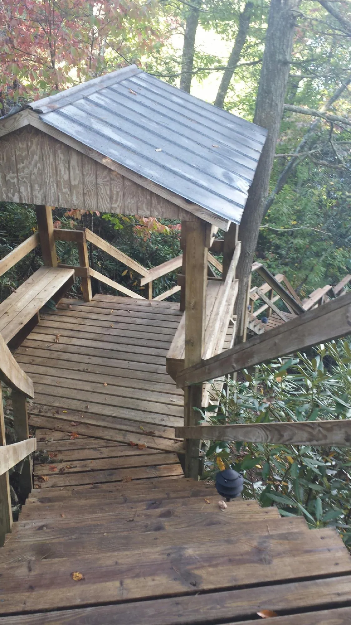 Metal roofed shelter over wooden steps on a wooded walkway — Skylight Repair & Installation work by our crew in Hanover Park