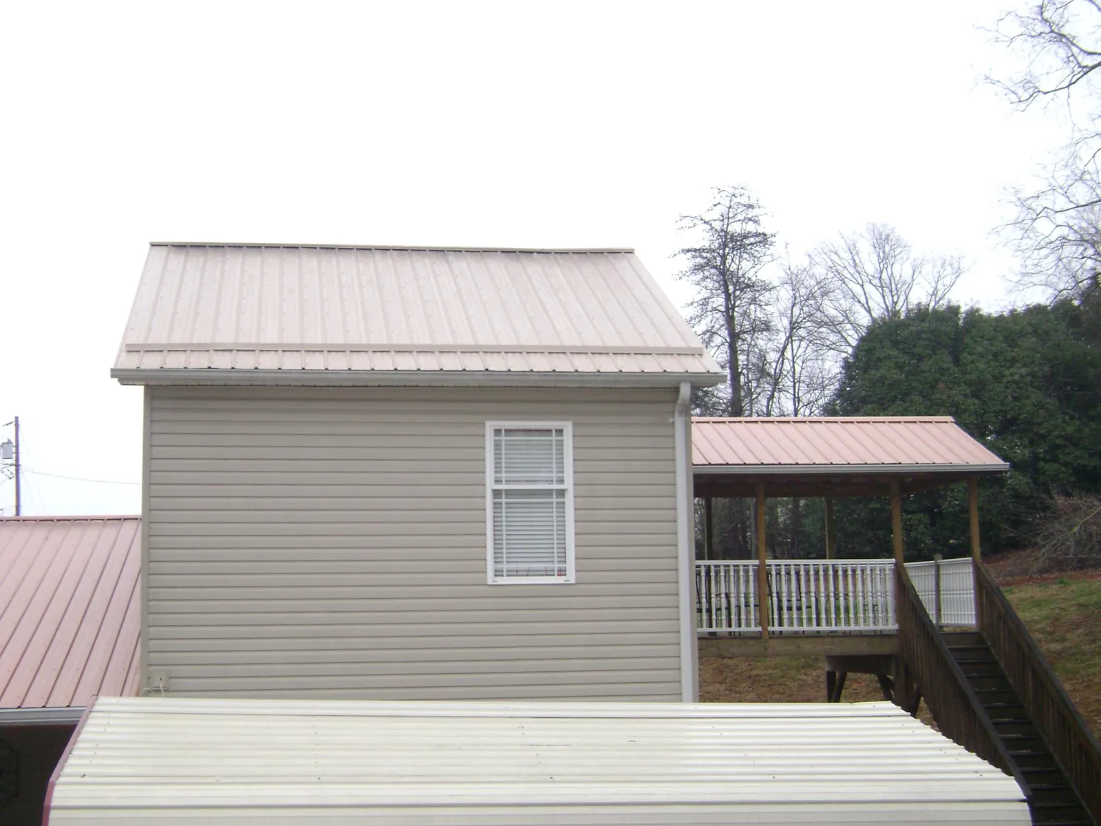 Tan metal roofs on a two story addition and attached porch, from a Roof Replacement job in Hanover Park