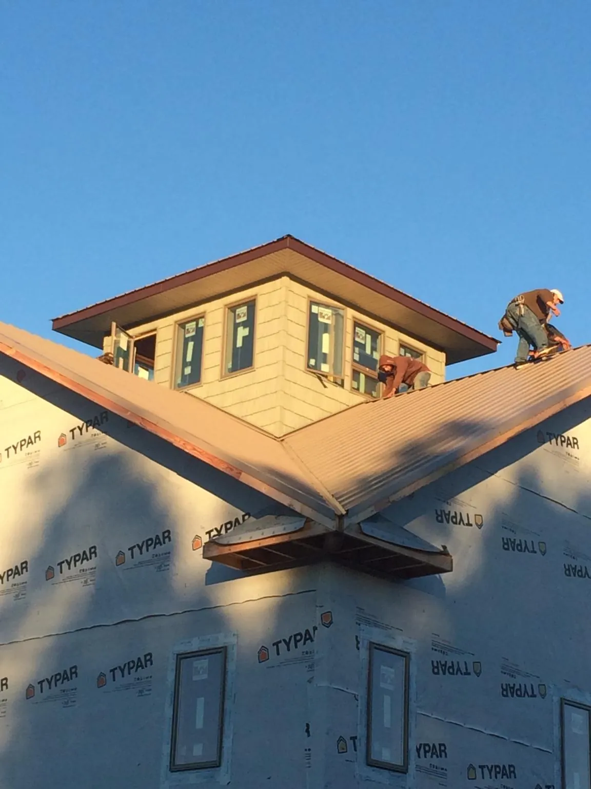 Roofers working around a rooftop cupola on a new metal roof at sunset — Roof Waterproofing in Hanover Park by Roofing Brothers